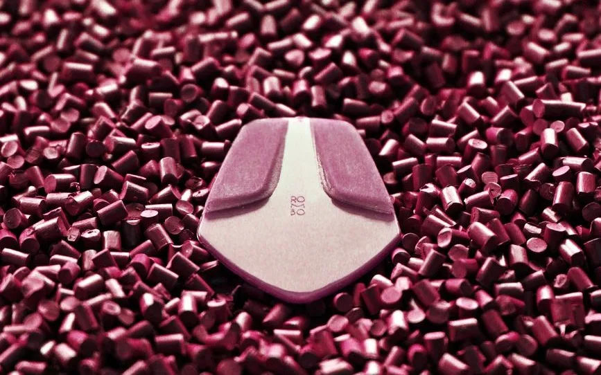 Plastic resin pellets beside a finished moulded part